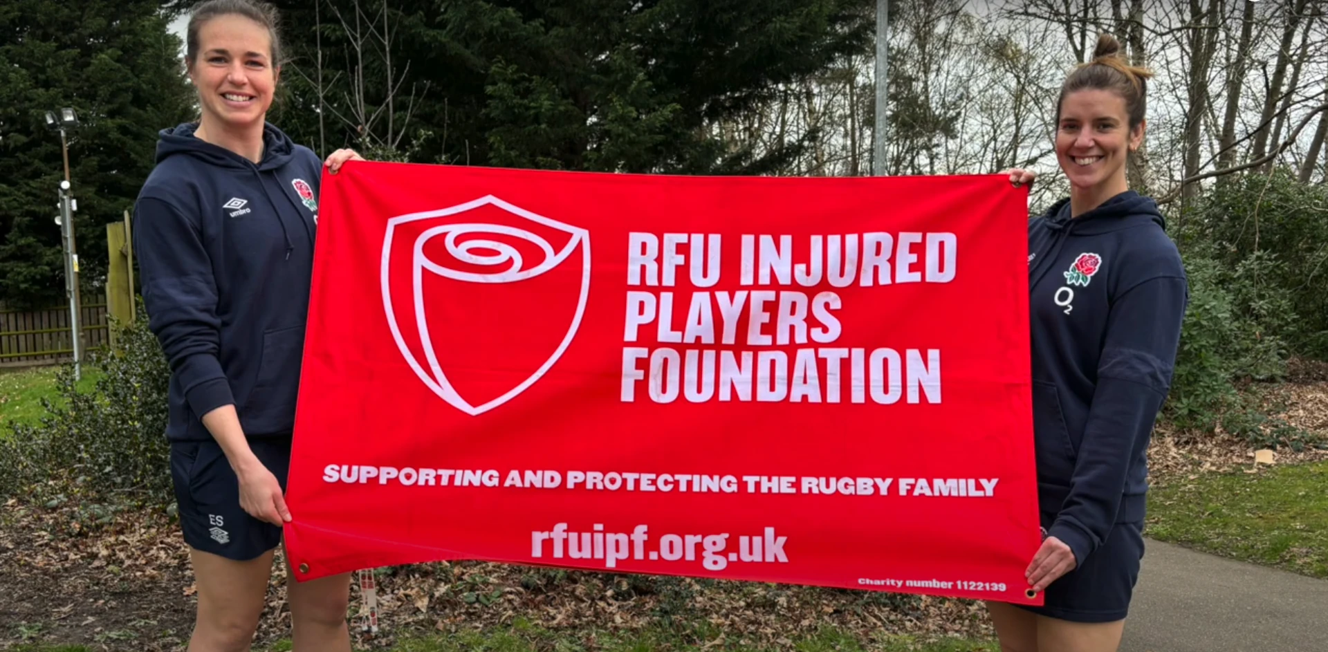 Emily Scarrat and Sarah Hunter holding a RFU Injured Players Foundation flag